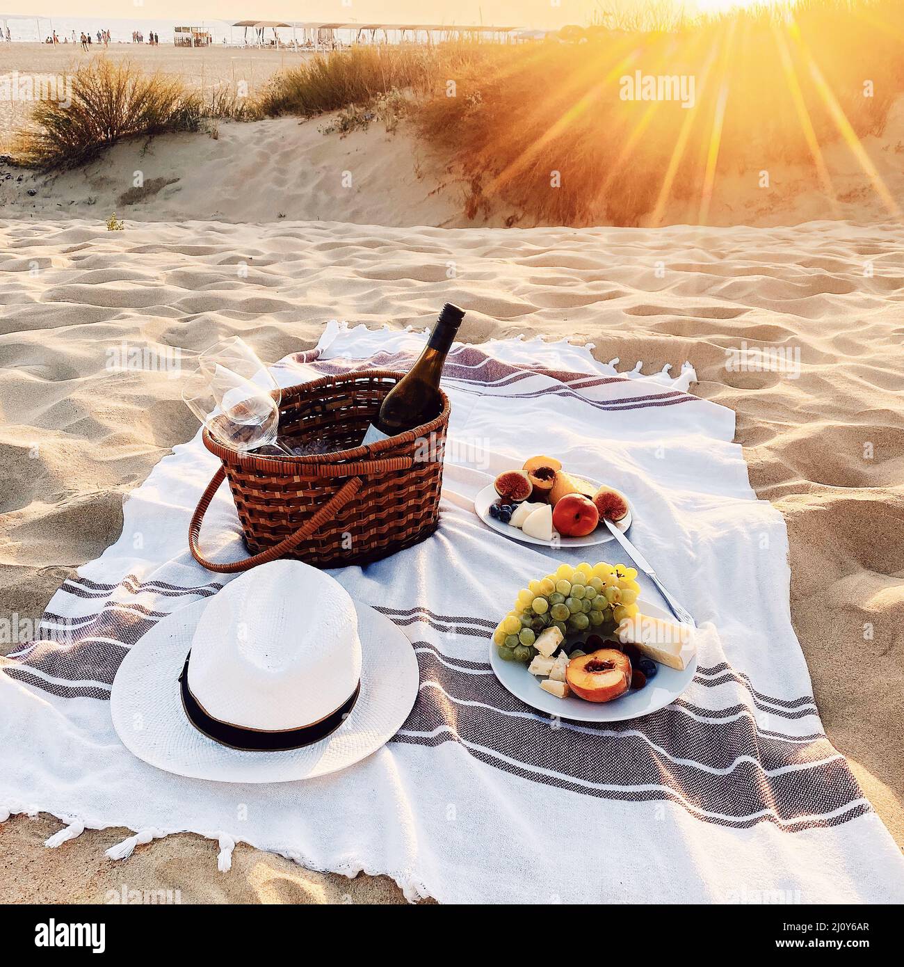 Romantic picnic with wine on sandy beach at amazing evening sunset Stock Photo