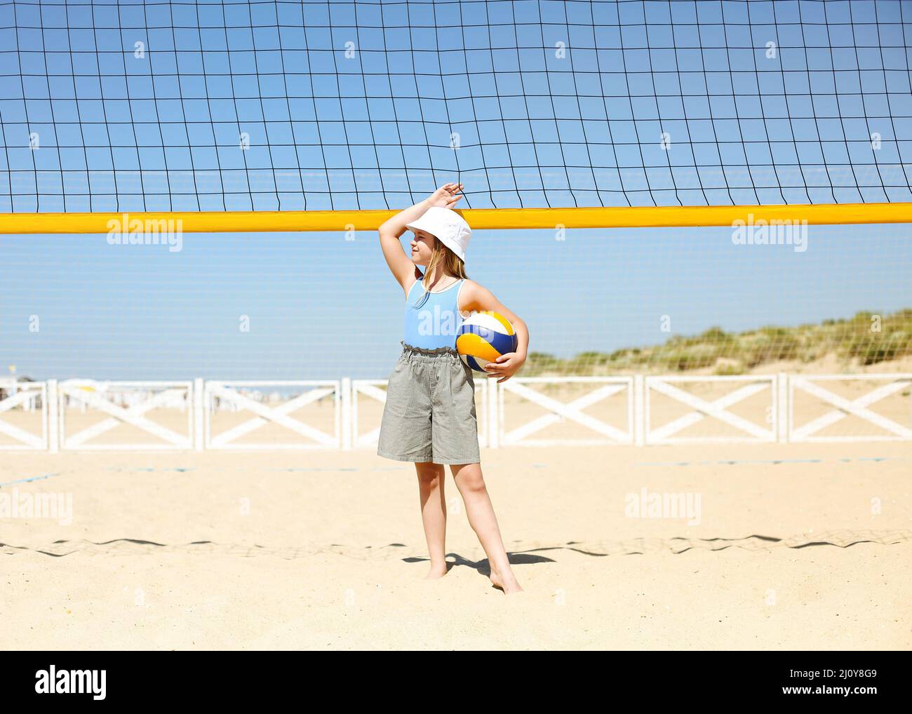 Little blond active girl plays volleyball on the beach with a ball Stock Photo