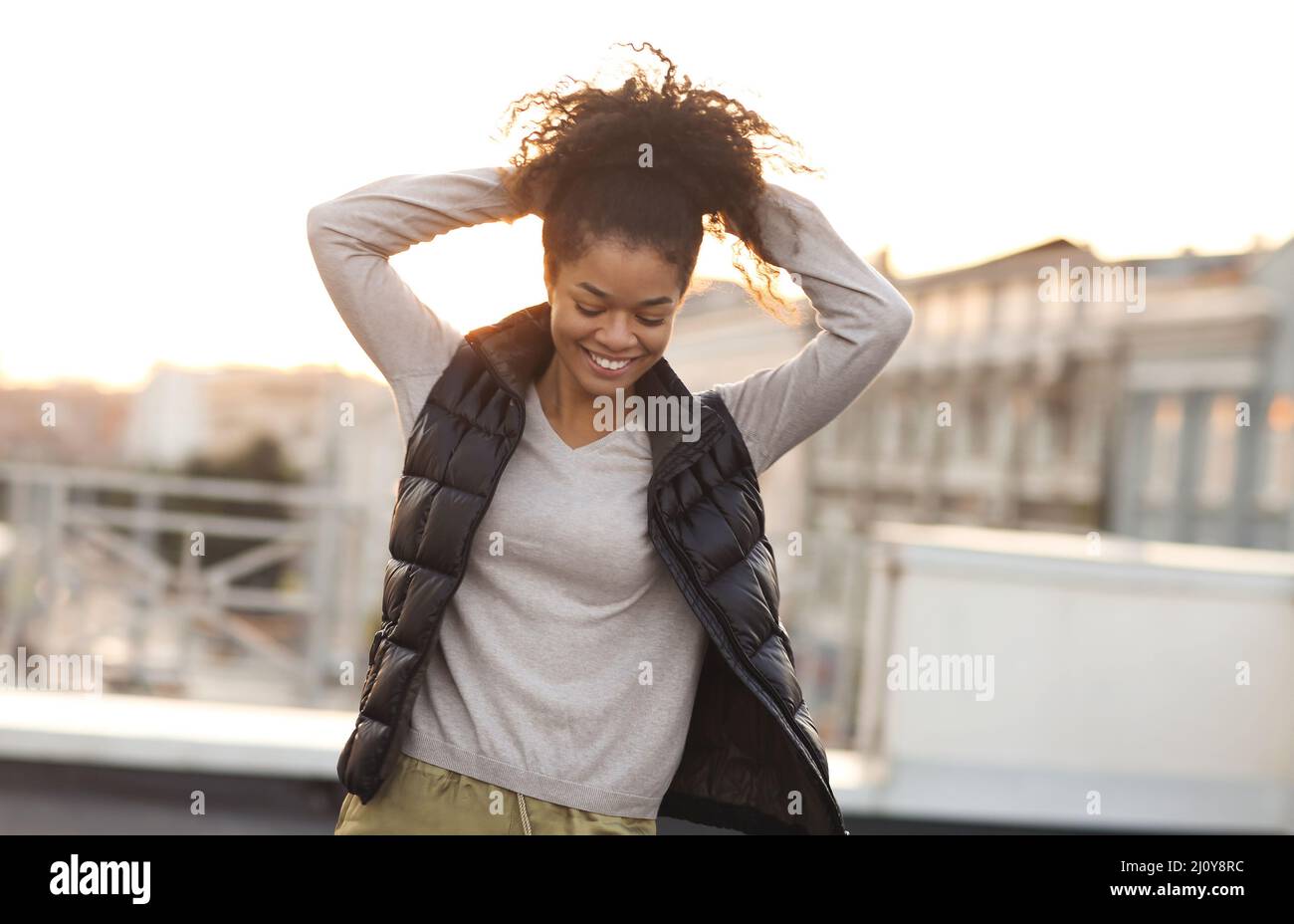 Young happy carefree african american woman dancing having fun at rooftop in morning sunlight Stock Photo