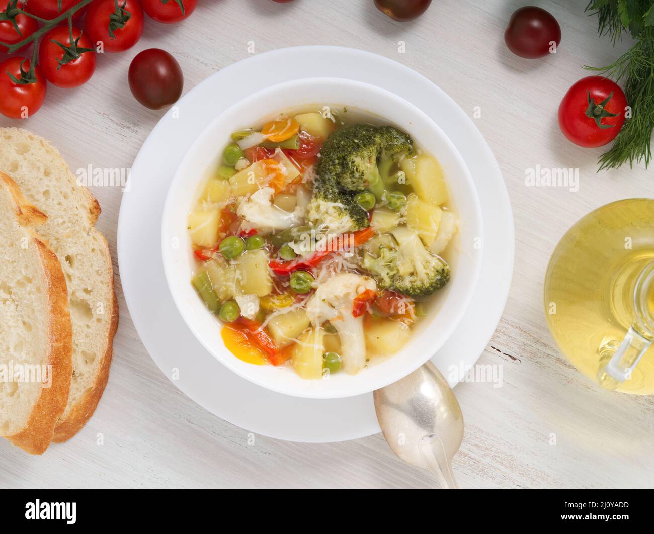 Minestrone soup. Vegetable soup with tomato, celery, carrot, zucchini, onion, pepper, broccoli. Top view, white backdrop Stock Photo