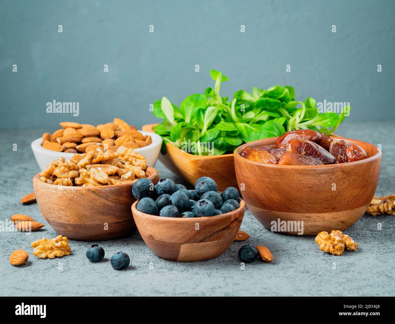 Healthy vegan food dry fruits, greens, nuts, berry. Superfoods on gray stone background, side