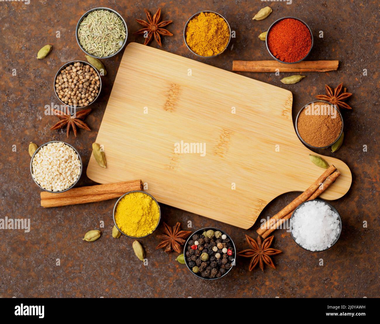 Various Indian spices in metal cups. Empty wooden Board, top view, space for text. Stock Photo