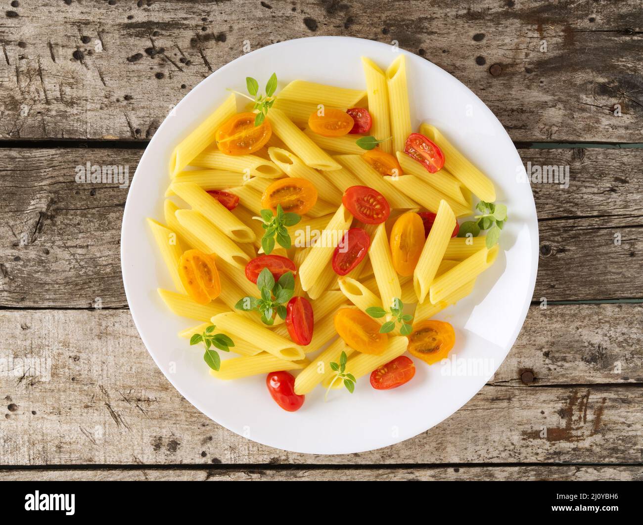 Penne pasta with tomatoes decorated with basil on old rustic gray wooden background, low-calorie diet, top view Stock Photo