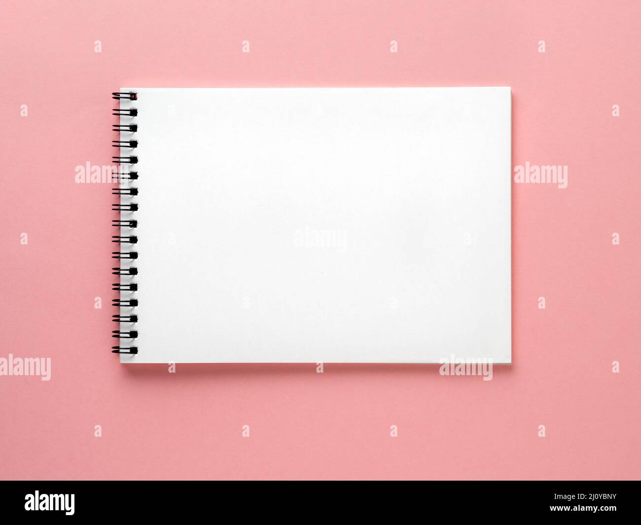 Blank notepad white page on pink desk, color background. Top view, flat