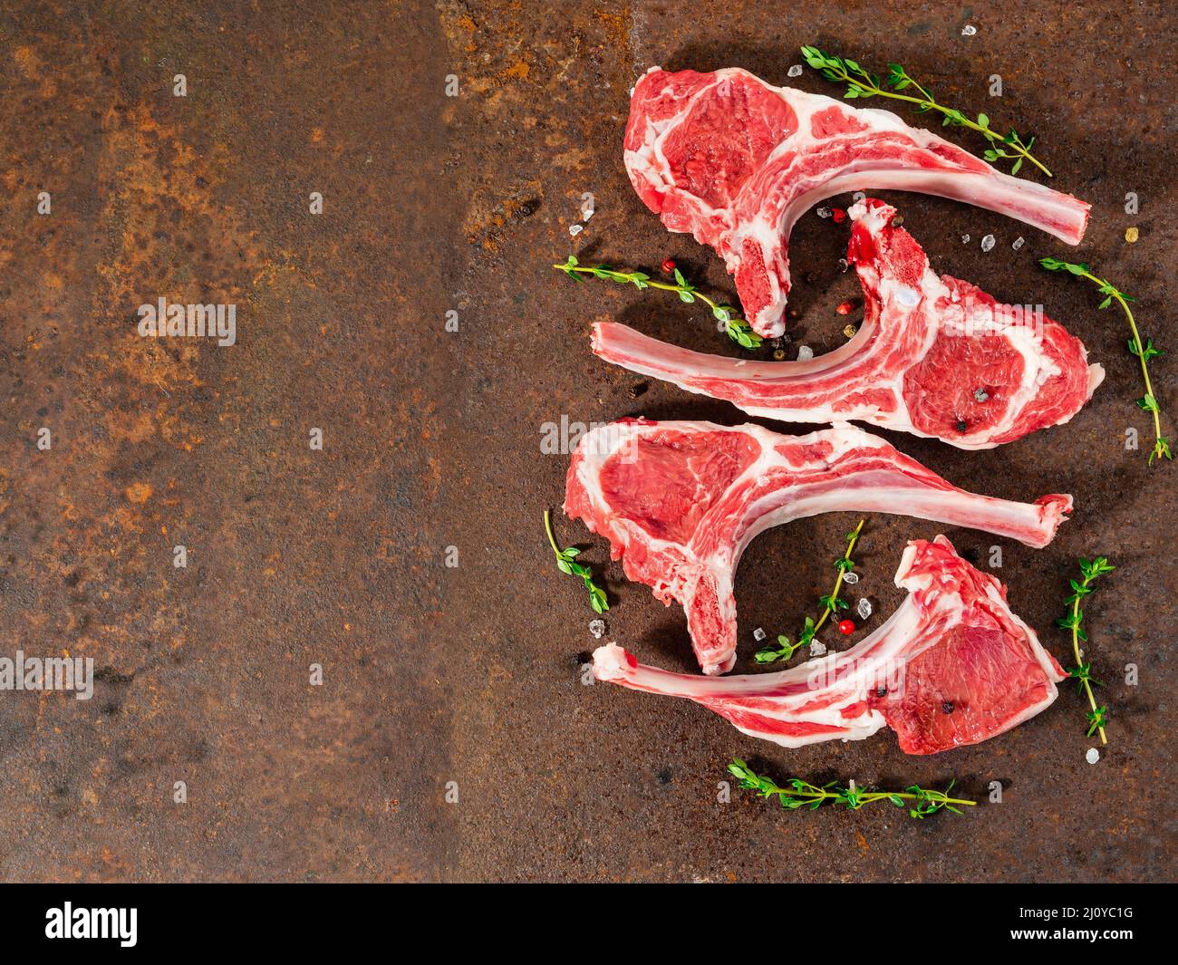 Raw lamb cutlets on bone on dark metallic background, top view, empty space. Stock Photo
