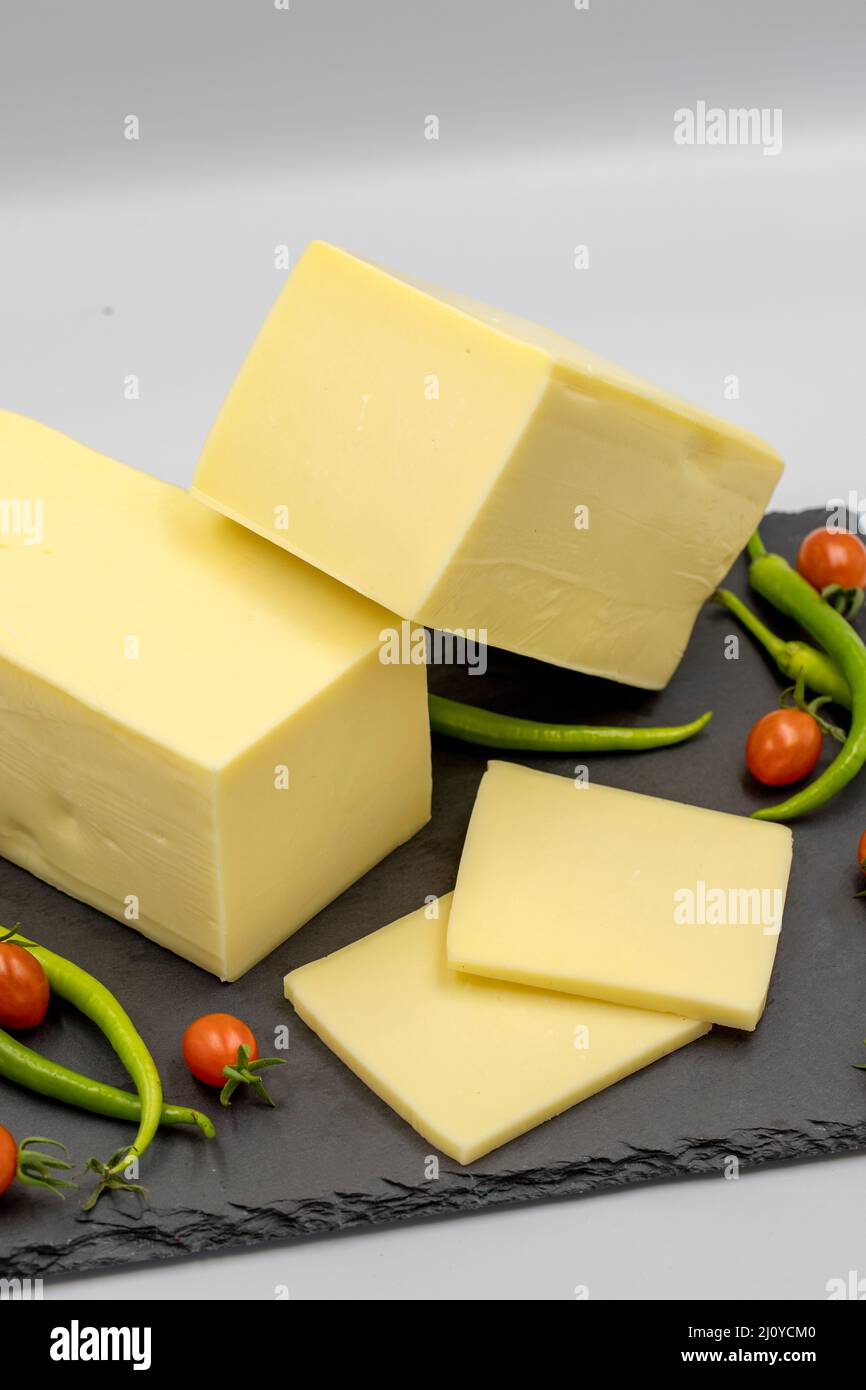 Cheddar cheese or kashkaval cheese on white background. Cheese slices on the serving board Stock Photo