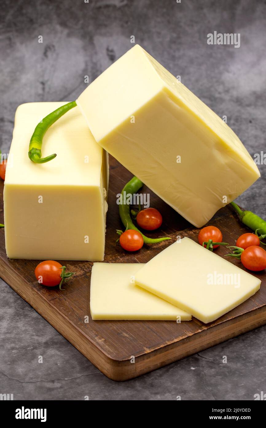 Cheddar cheese or kashkaval cheese on dark background. Cheese slices on the serving board Stock Photo