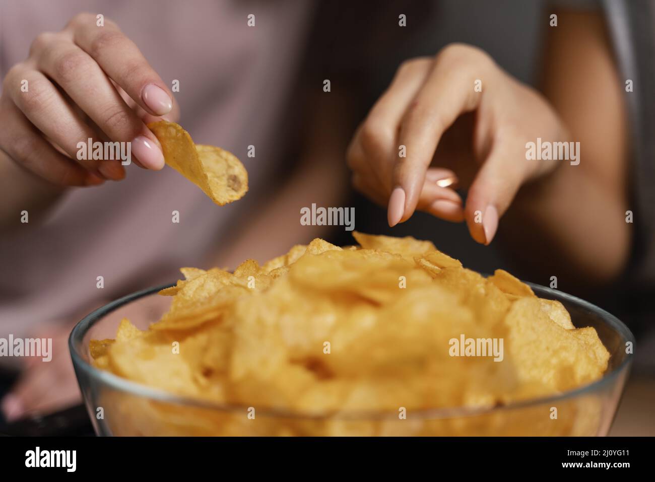 Women couch watching tv eating chips close up. High quality photo Stock Photo