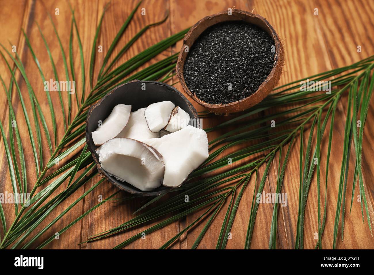 Coconut shells with activated carbon on wooden background Stock Photo