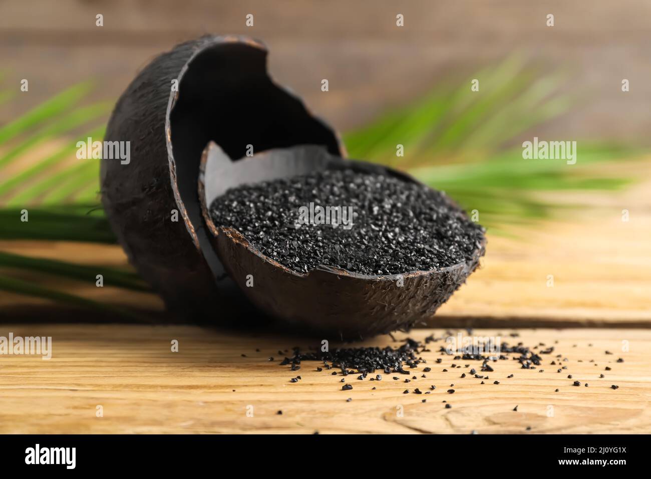 Coconut shells with activated carbon on wooden background Stock Photo