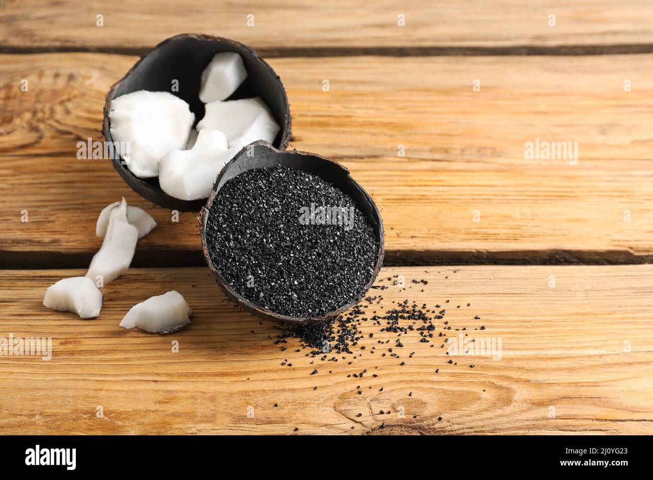 Coconut shells with activated carbon on wooden background Stock Photo
