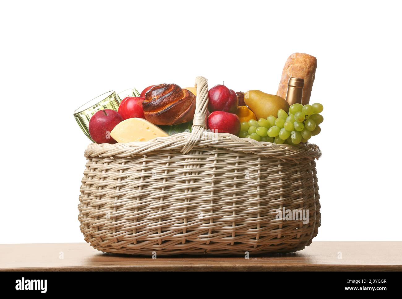 Wicker basket with tasty food for picnic on table against white ...