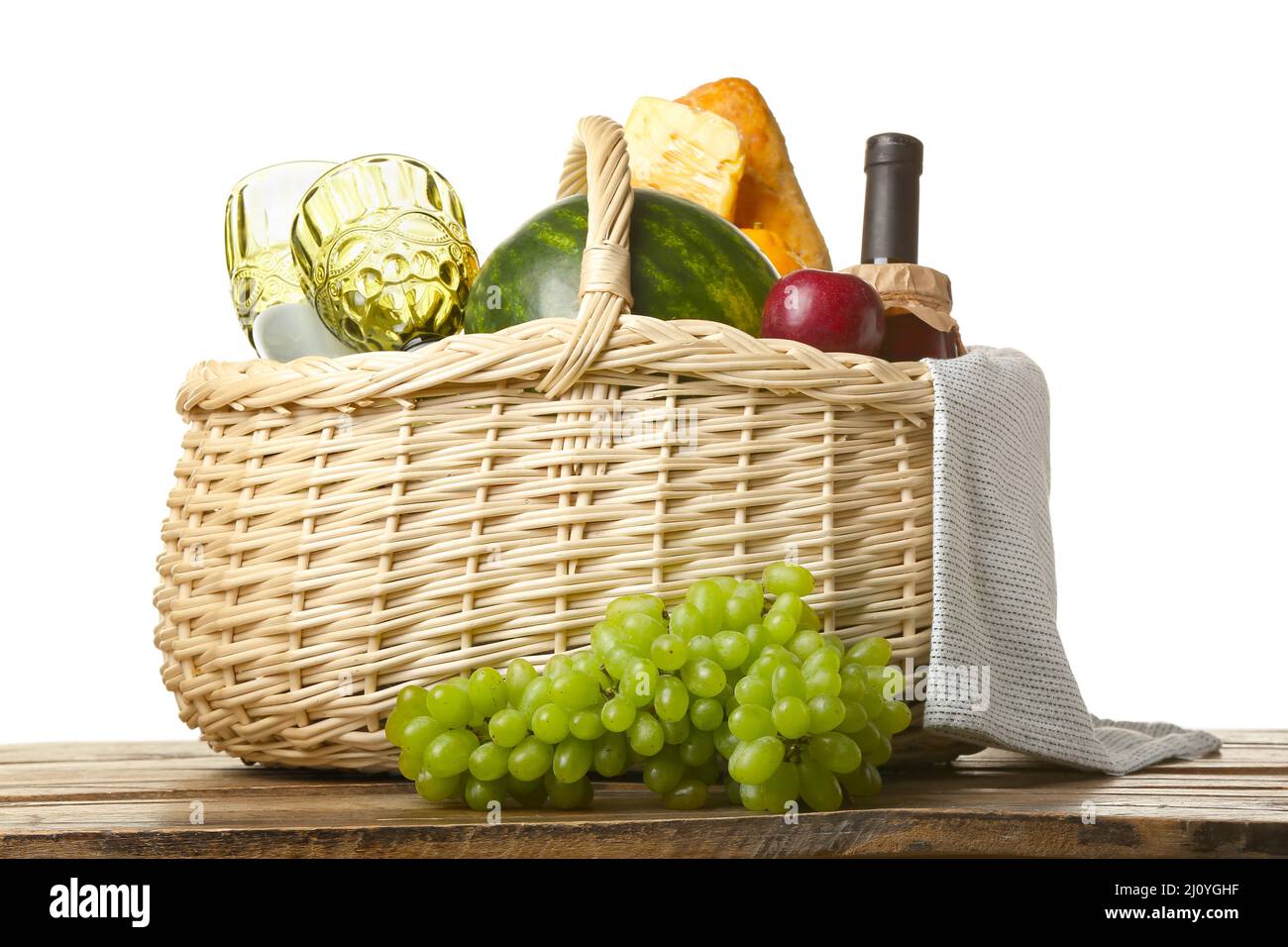 Wicker basket with tasty food for picnic on table against white ...