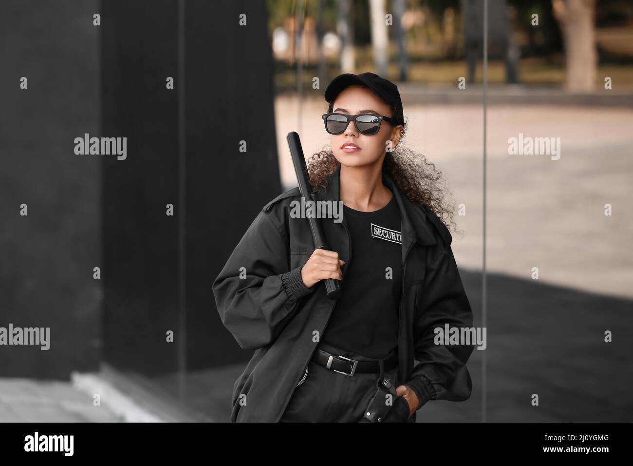 African-American female security guard with baton near building ...