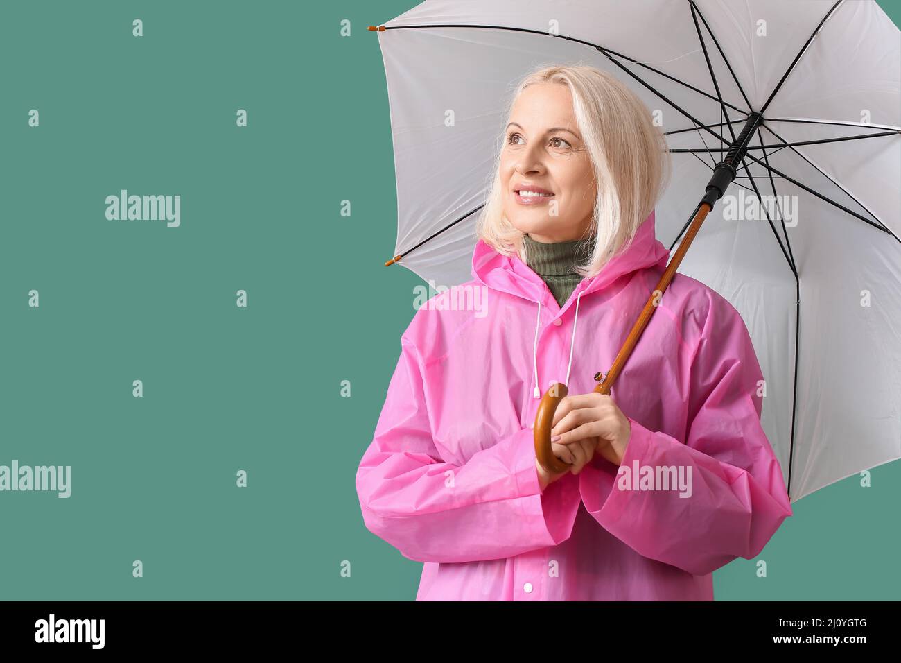 Beautiful mature woman in raincoat and with umbrella on color