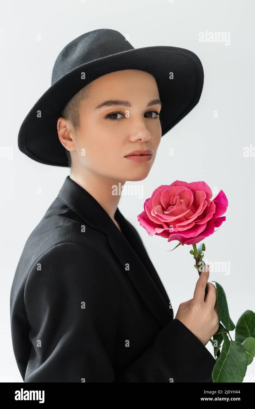 charming woman with natural makeup, wearing black fedora hat, holding