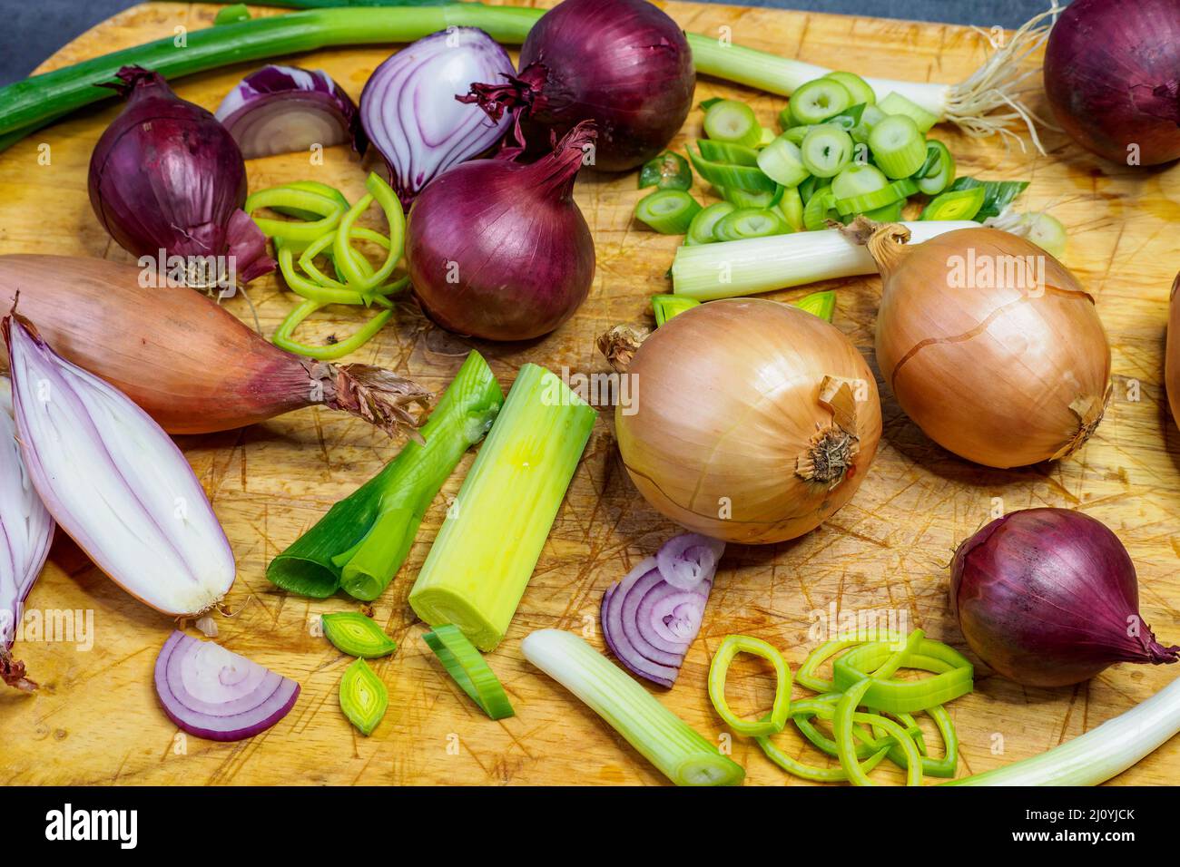 Different types of onion on wooden table. Onions, shallots, red and