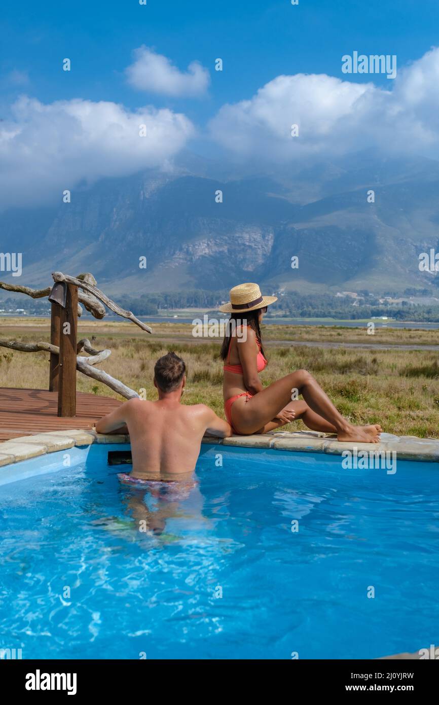 Couple man and woman in swimming pool of there lodge on vacation in South Africa looking out over mountains near Hermanus Stock Photo
