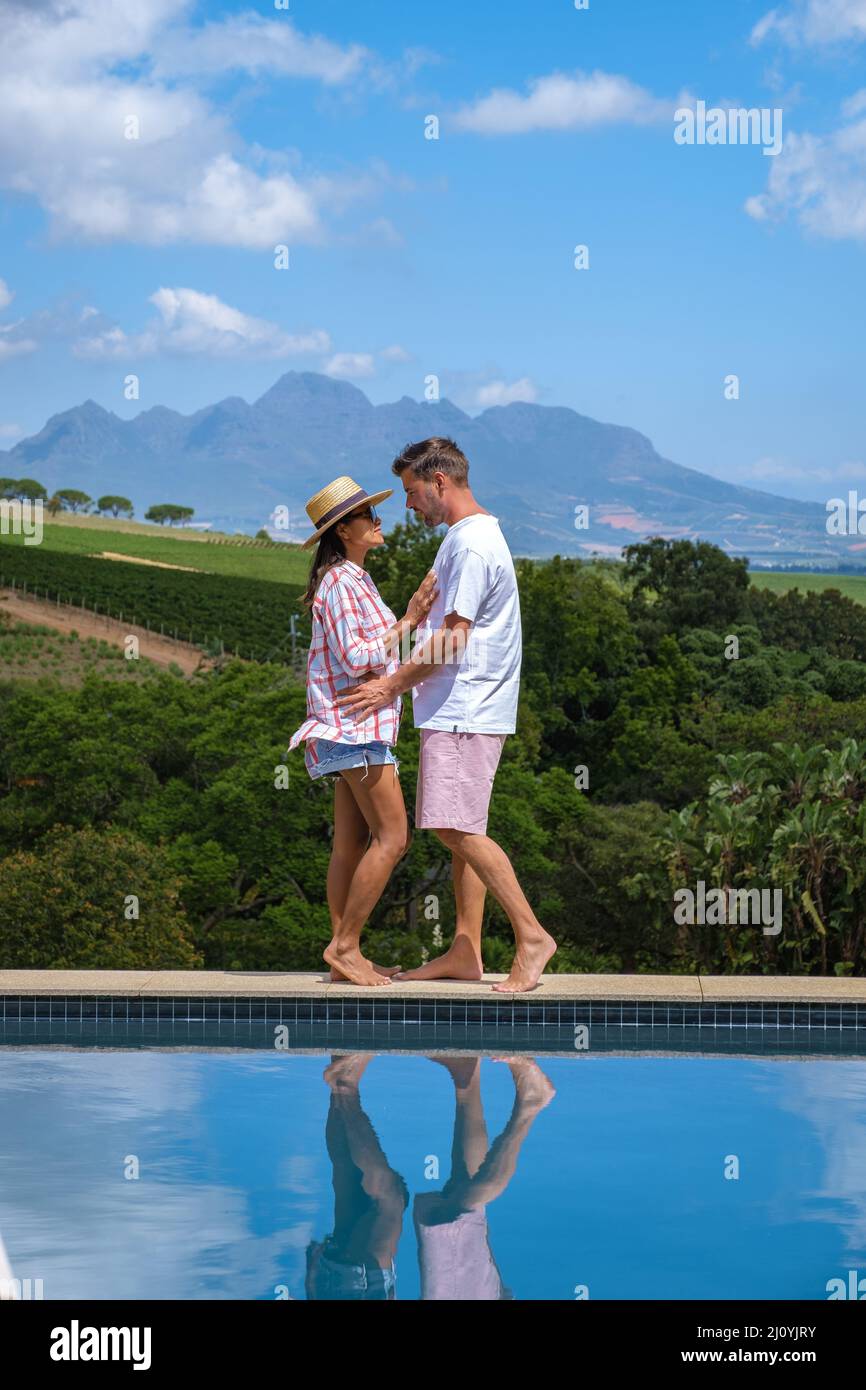 Couple man and woman in swimming pool looking out over the Vineyards and mountains of Stellenbosch South Africa Stock Photo