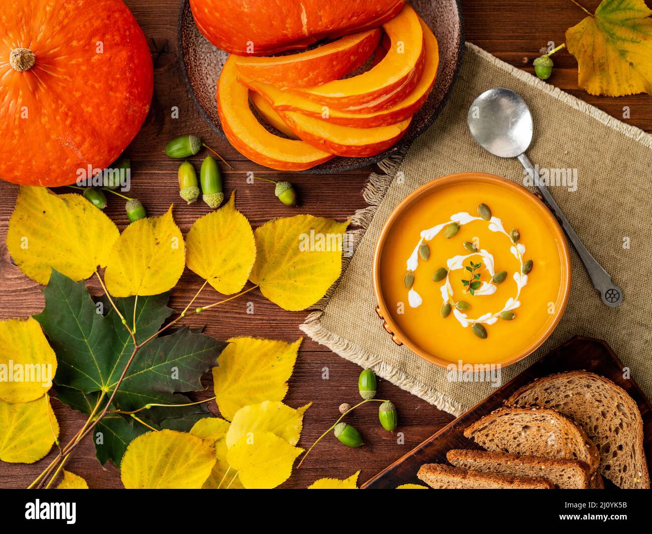 Autumn food. Pumpkin puree soup, leaves, dark brown old wooden table, top view. Stock Photo