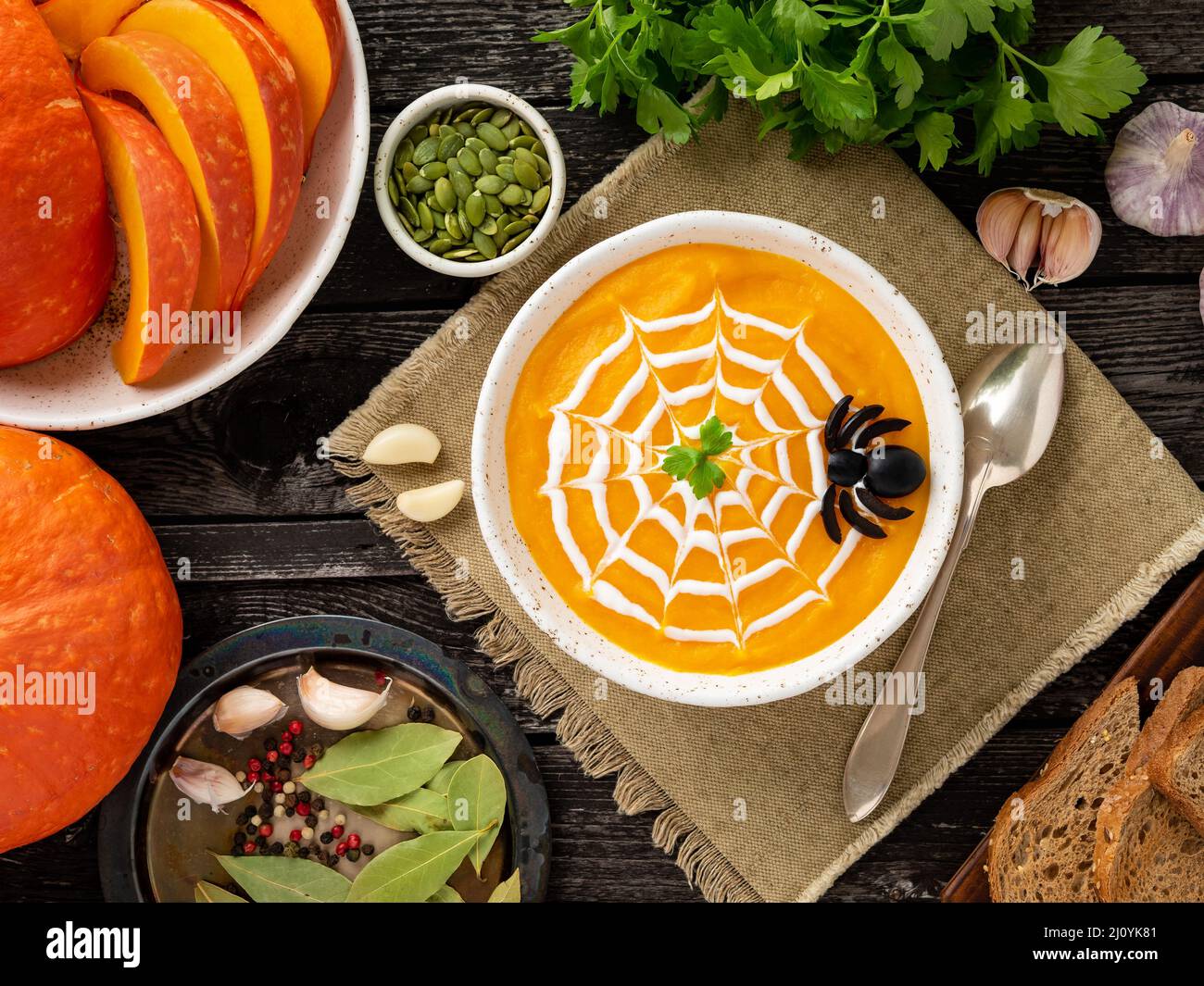 Funny food for Halloween. Pumpkin puree soup, spider web, dark old wooden table, top view. Stock Photo