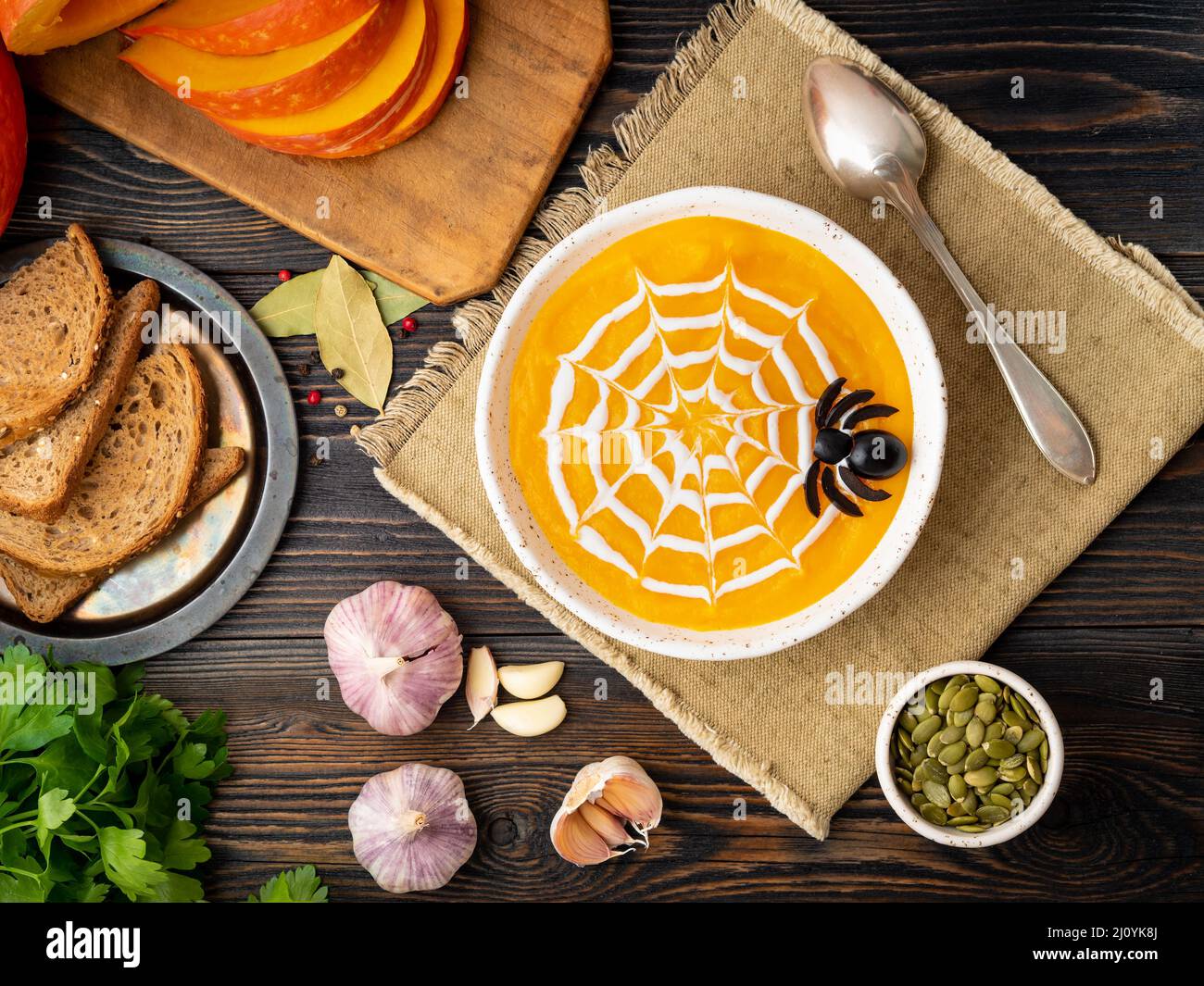 Funny food for Halloween. Pumpkin puree soup, spider web, dark old wooden table, top view. Stock Photo