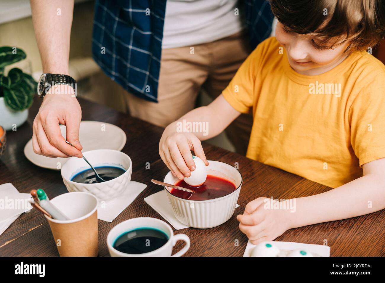 Easter day. Male Father and son painting eggs on wooden background. Family sitting in a kitchen. Preparing for Easter, creative homemade decoration Stock Photo