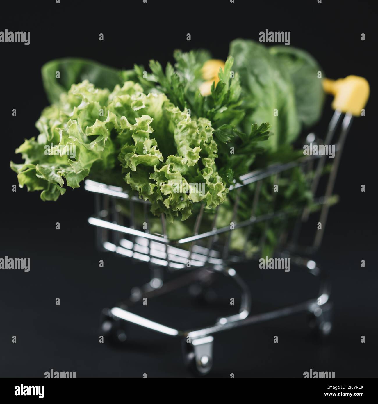 Close up green leafy vegetables shopping cart black backdrop. High quality photo Stock Photo