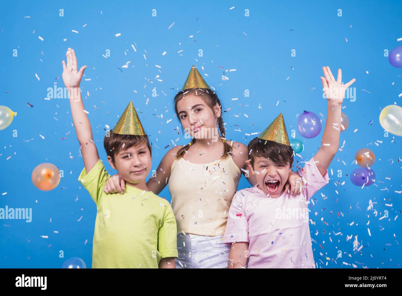 Close up cheerful siblings with confetti balloons blue backdrop. High quality photo Stock Photo