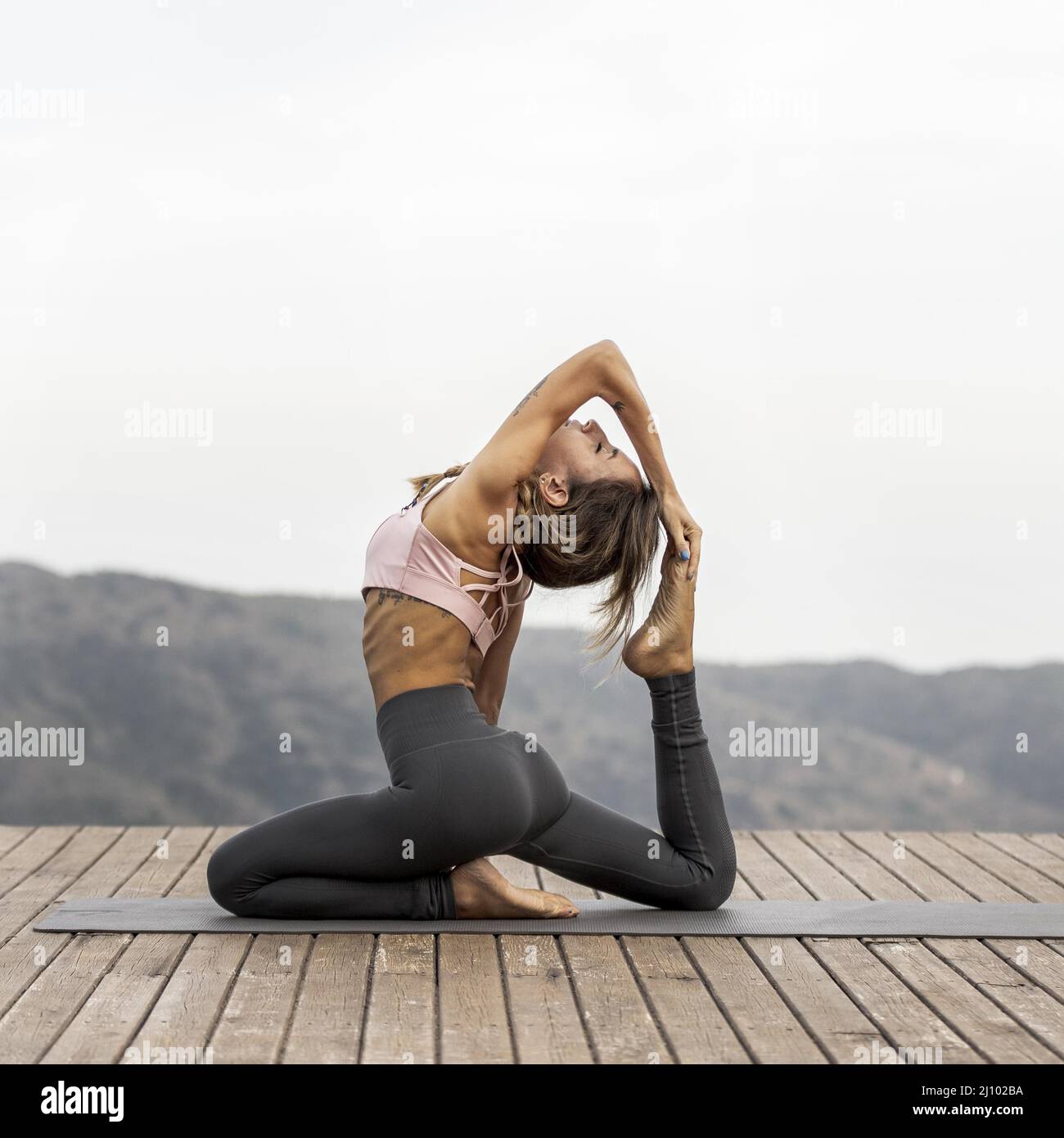 Side view woman doing yoga outdoors Stock Photo