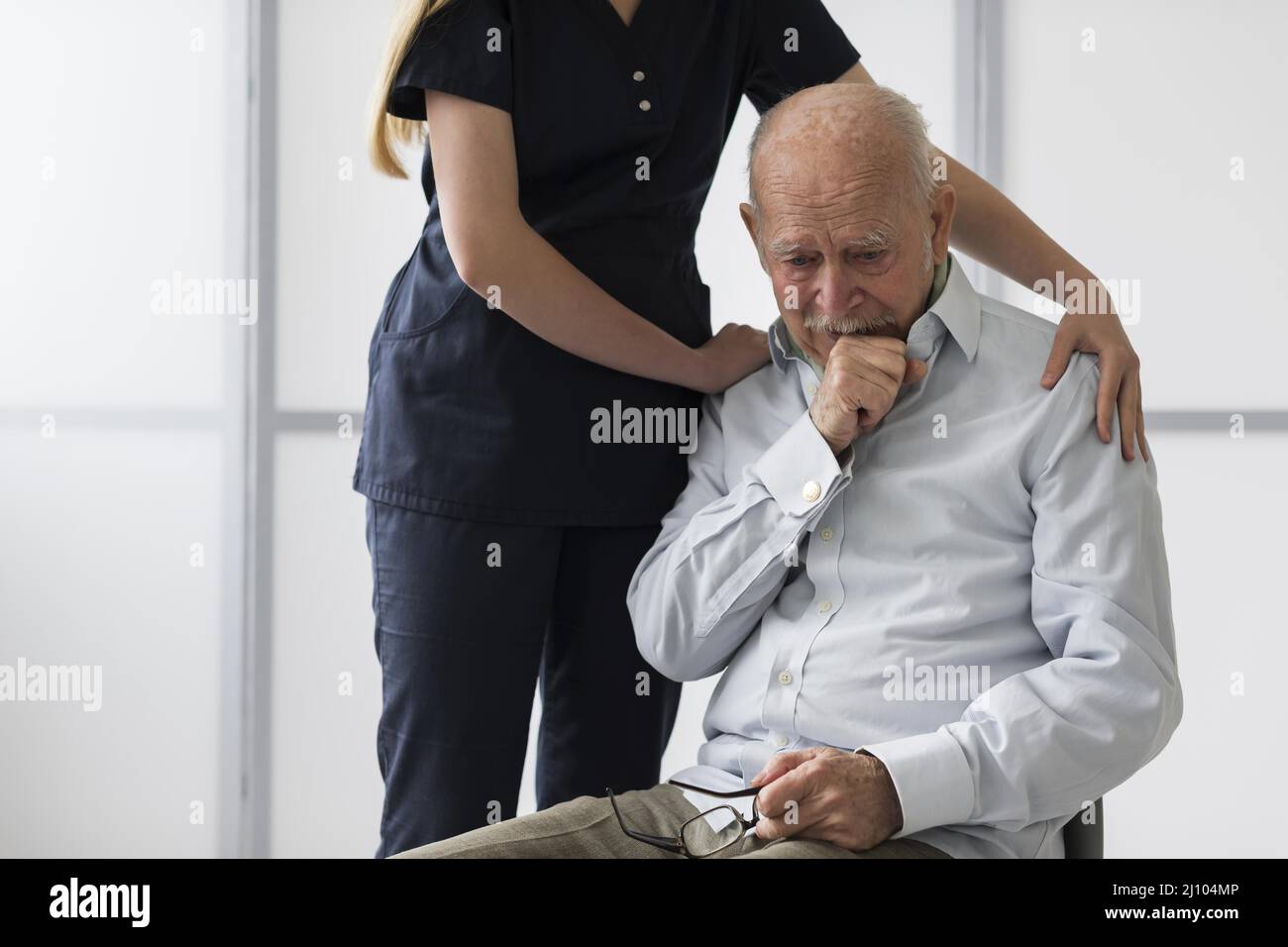 Nurse consoling old crying man Stock Photo