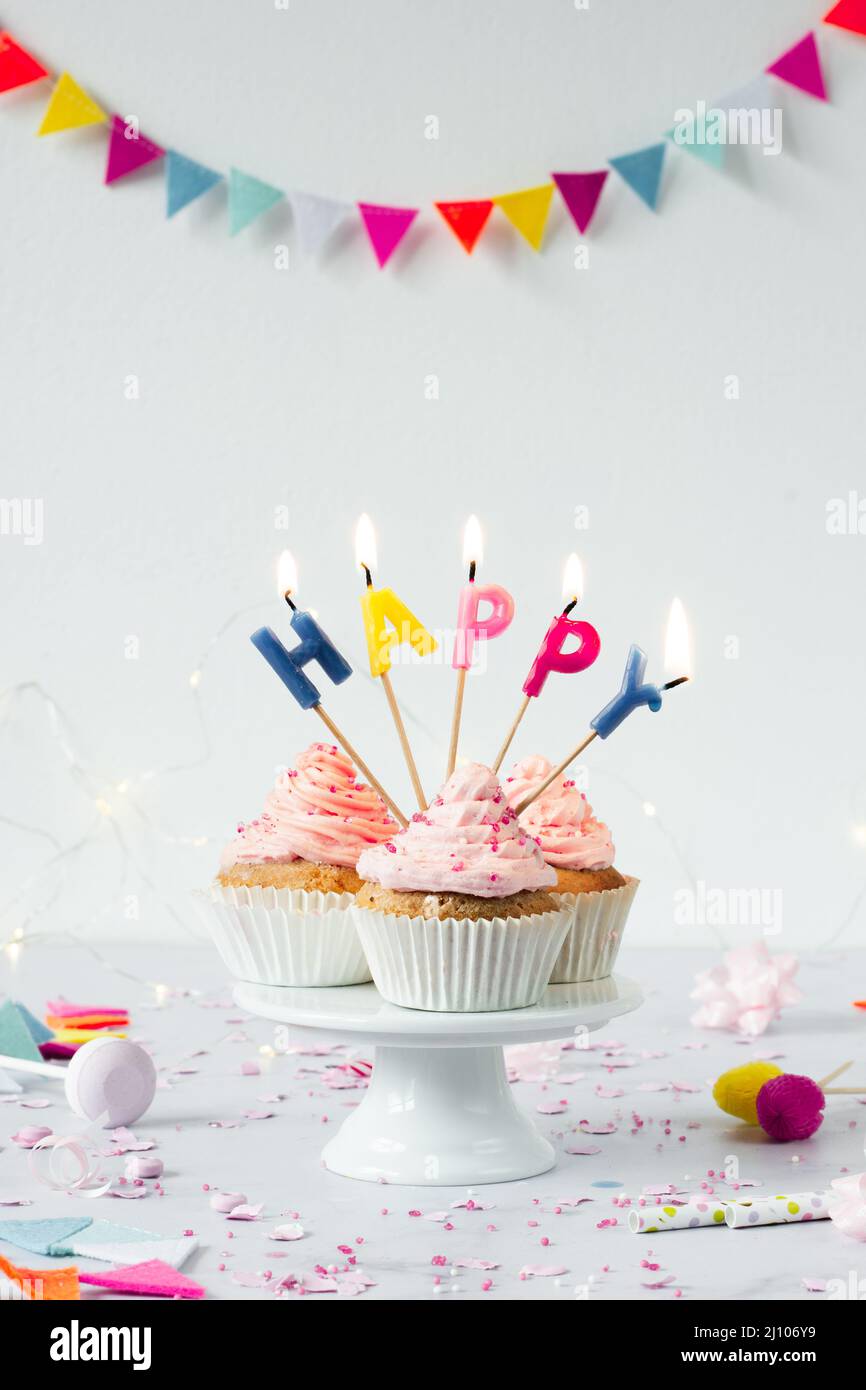 Front view birthday cupcakes with lit candles Stock Photo