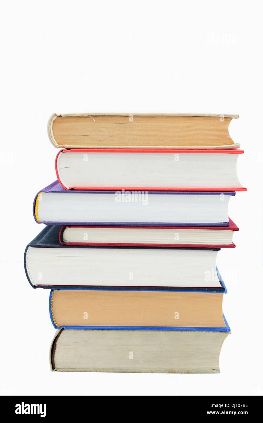 Closeup shot of seven books stacked over one another on a white background Stock Photo
