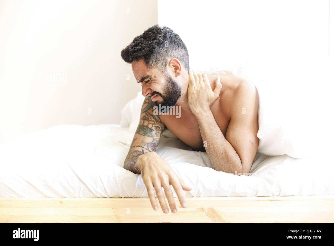 Man lying bed suffering from neck pain Stock Photo