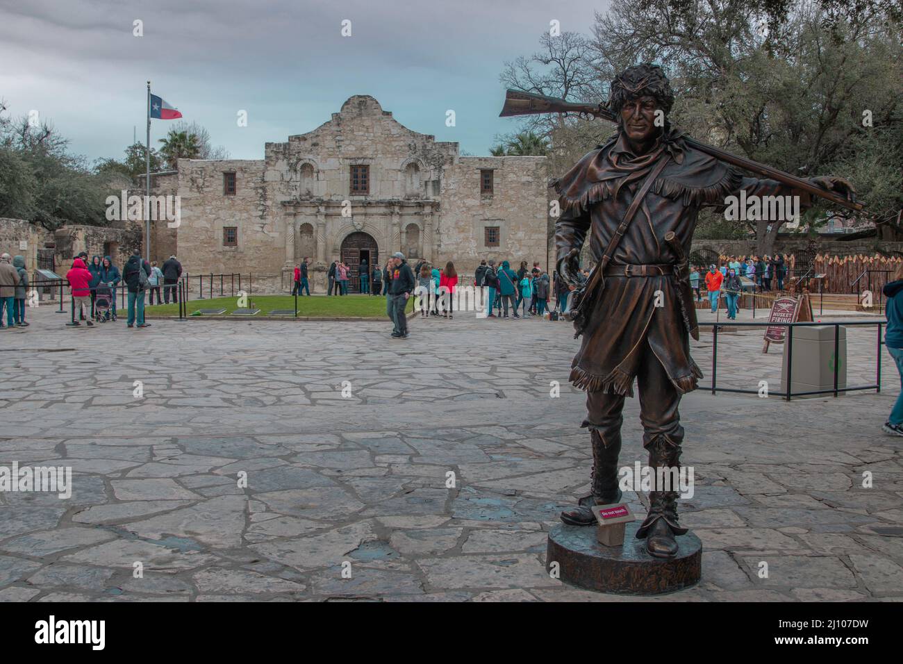 Visitors pass by a statue of Davy Crockett honoring those who fell at the Alamo Stock Photo