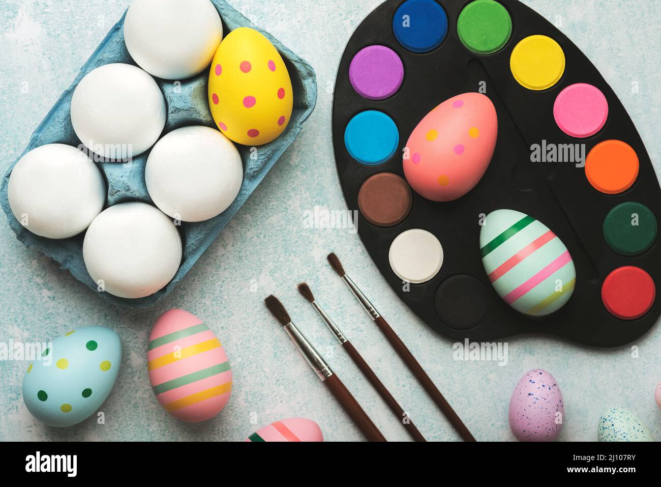 Happy Easter. Colored easter painted eggs with watercolors and brushes on a blue table Stock Photo