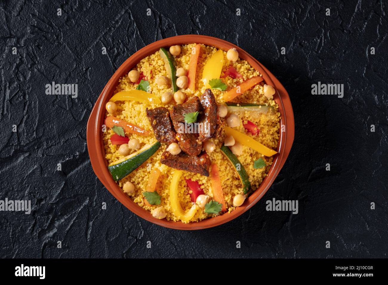 Meat and vegetable couscous, traditional Moroccan food, shot from the top, with chickpeas on a black background Stock Photo