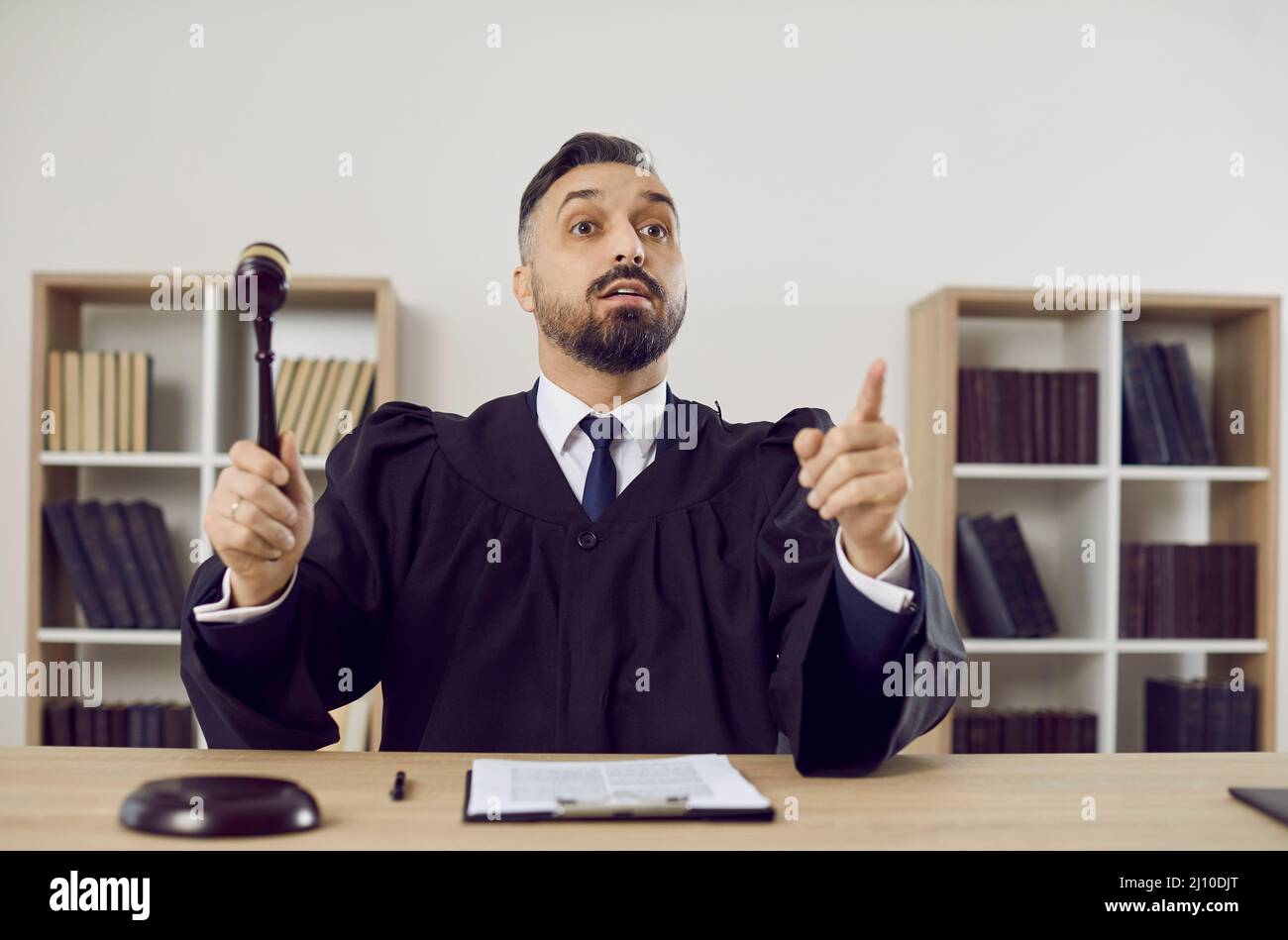 Judge in court of law pronounces his sentence and hits the sound block with his gavel Stock Photo