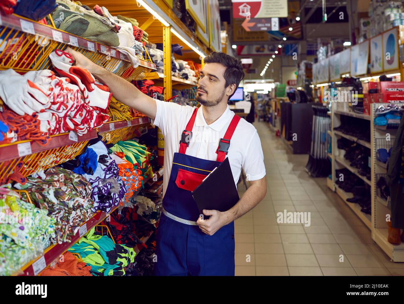 Salesman in uniform check goods on shelves in hypermarket Stock Photo