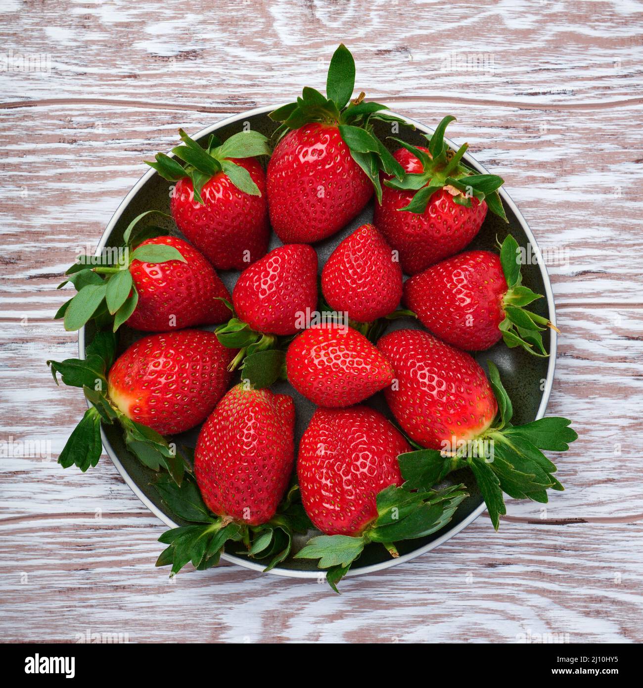 Ceramic plate full of fresh strawberries on wood table Stock Photo - Alamy