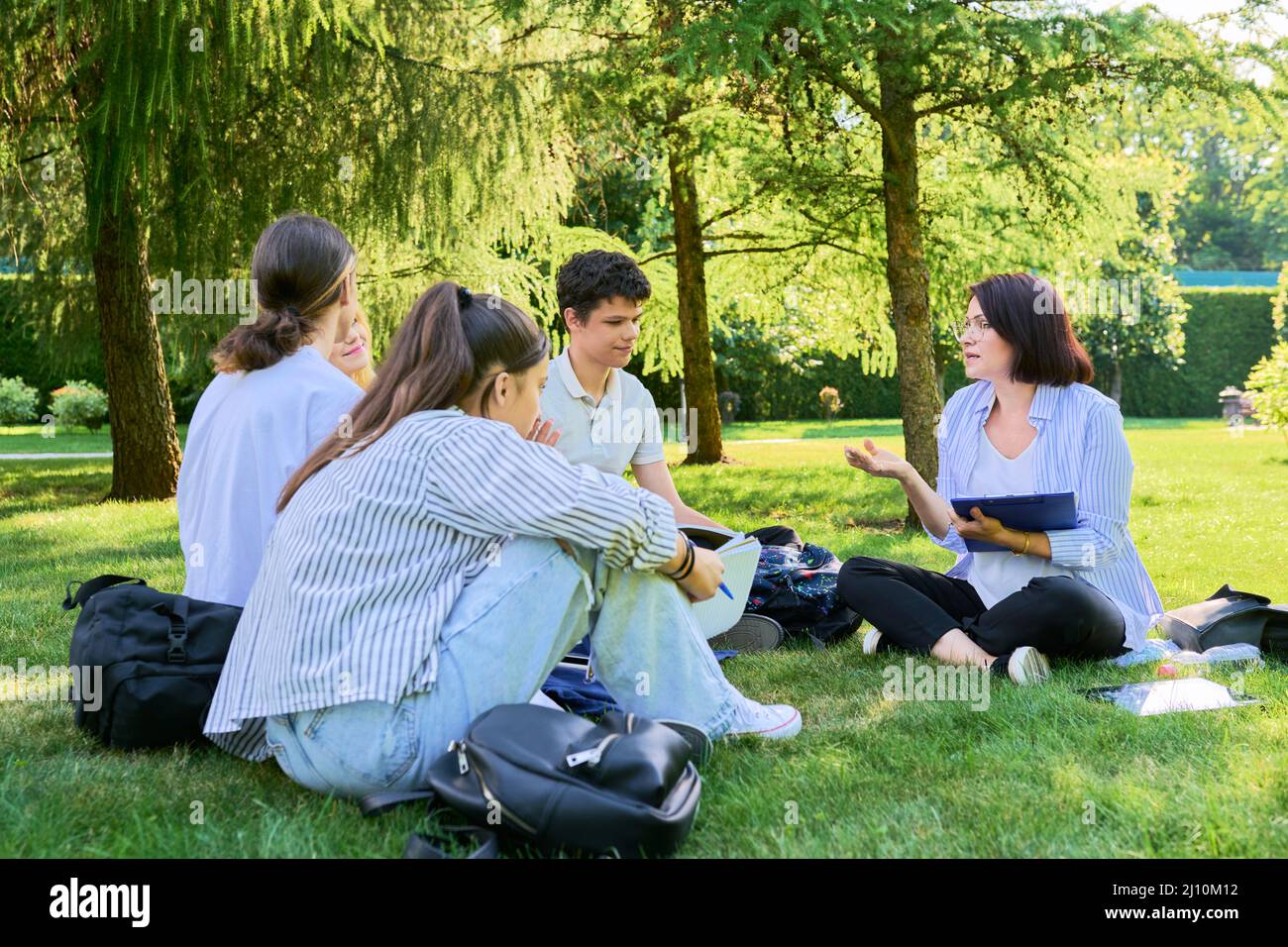 Outdoor, group of students with female teacher sitting on grass Stock ...