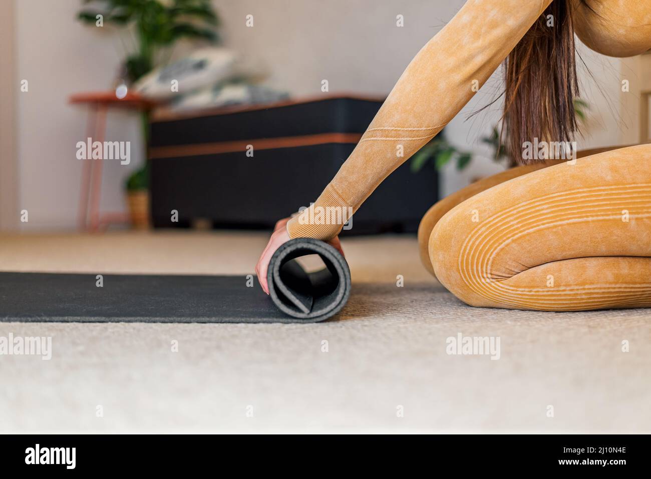 Picture of young girl, putting away her yoga mat after her morning exercise. Stock Photo