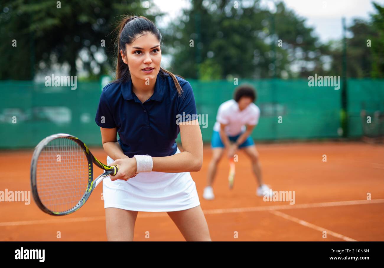 Tennis sport people concept. Mixed doubles player hitting tennis ball with partner standing near