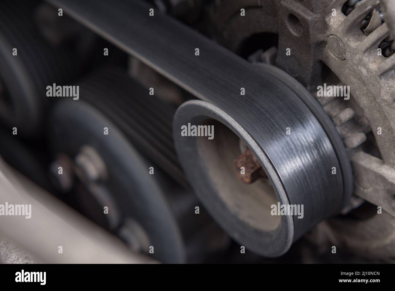Closeup of the drive belt and the alternator roller in the car engine