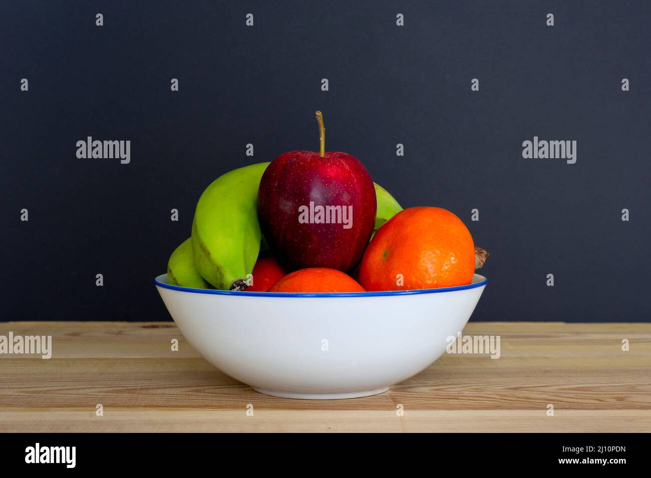 Bananas, apples and oranges in a bowl on a table. Stock Photo