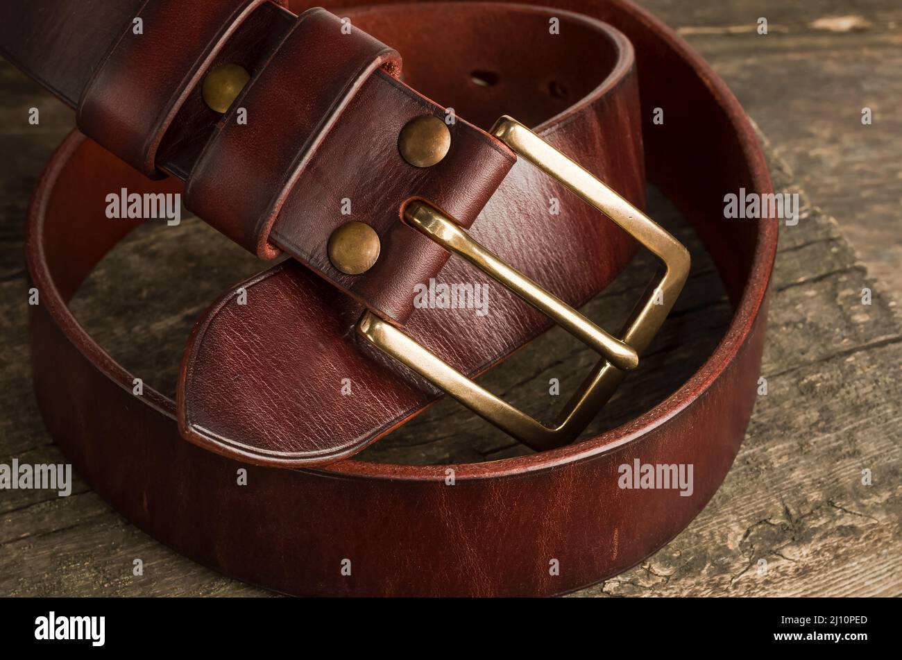 Men's leather trouser belt in brown color on an old vintage wooden background. Stock Photo