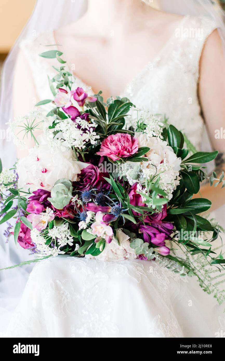 Bride carrying purple and pink wedding bouquet. Stock Photo