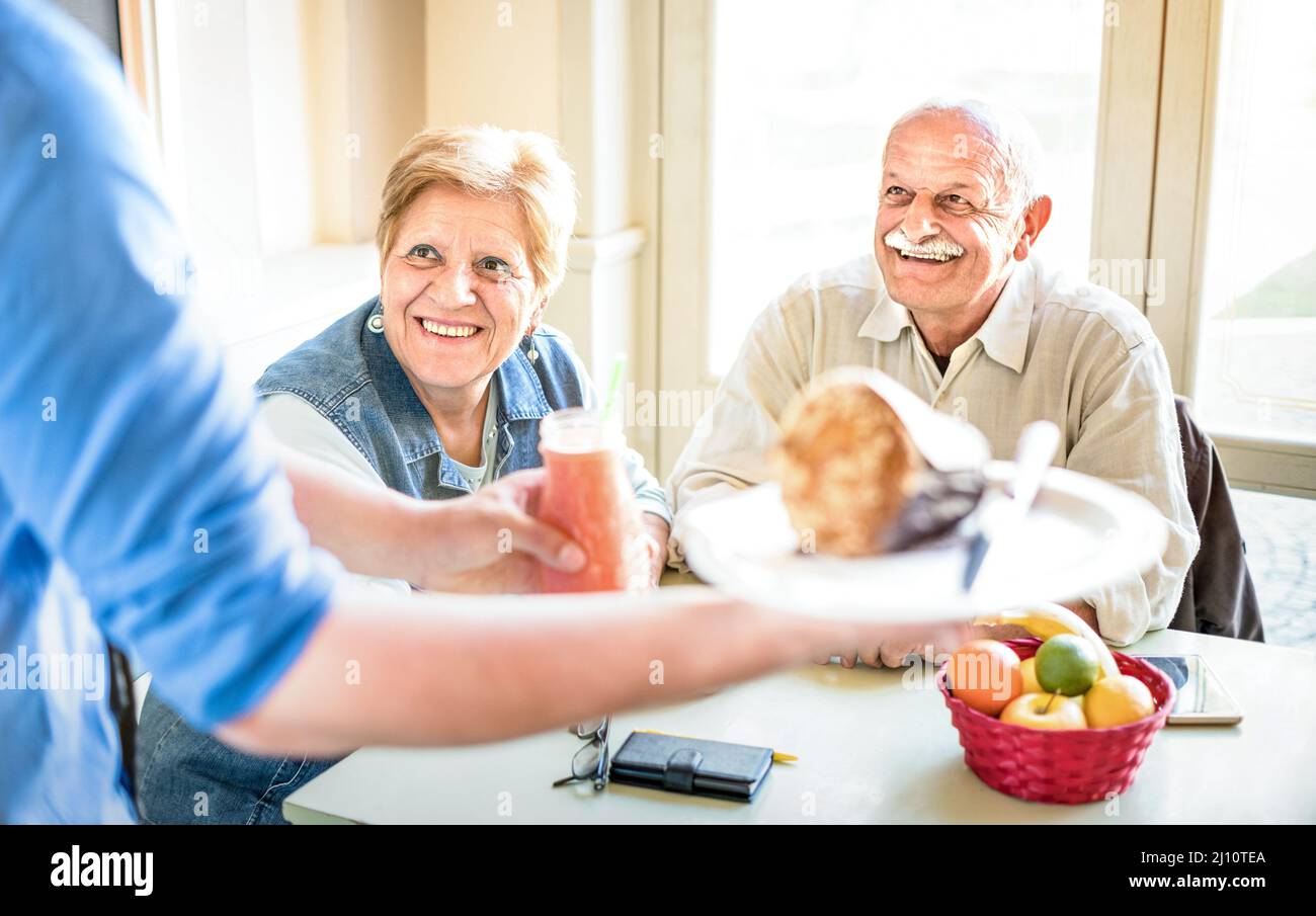 Waiter serving senior couple eating at vegan restaurant - Retired man ...