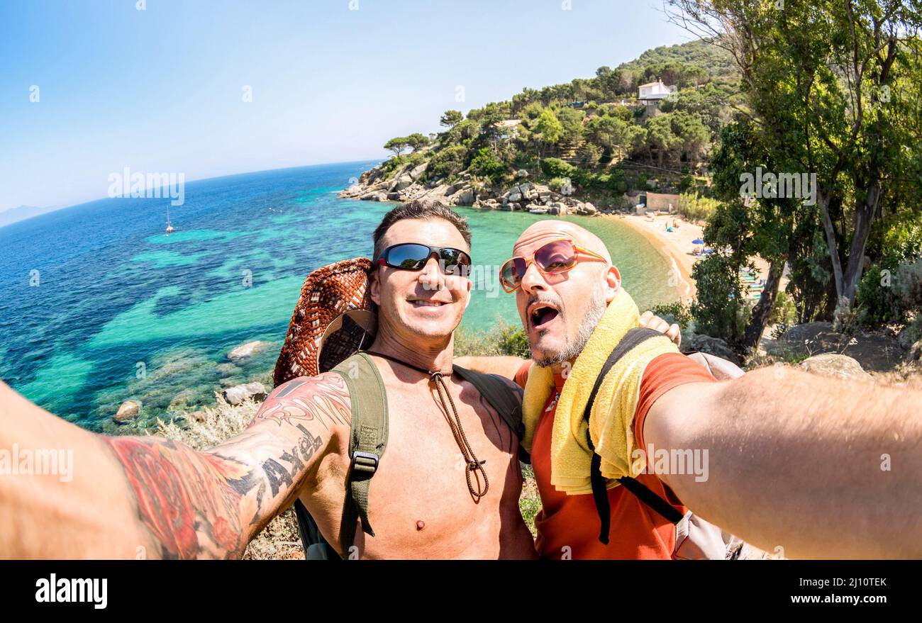Best friends taking selfie at Giglio Island on adventure travel - Wanderlust lifestyle concept with gay couple enjoying happy fun moment - Trip togeth Stock Photo