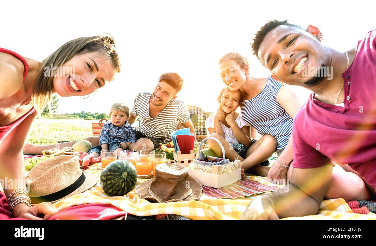 Happy multiracial families taking selfie at pic nic garden party - Multicultural joy and love concept with mixed race people having fun together at su Stock Photo